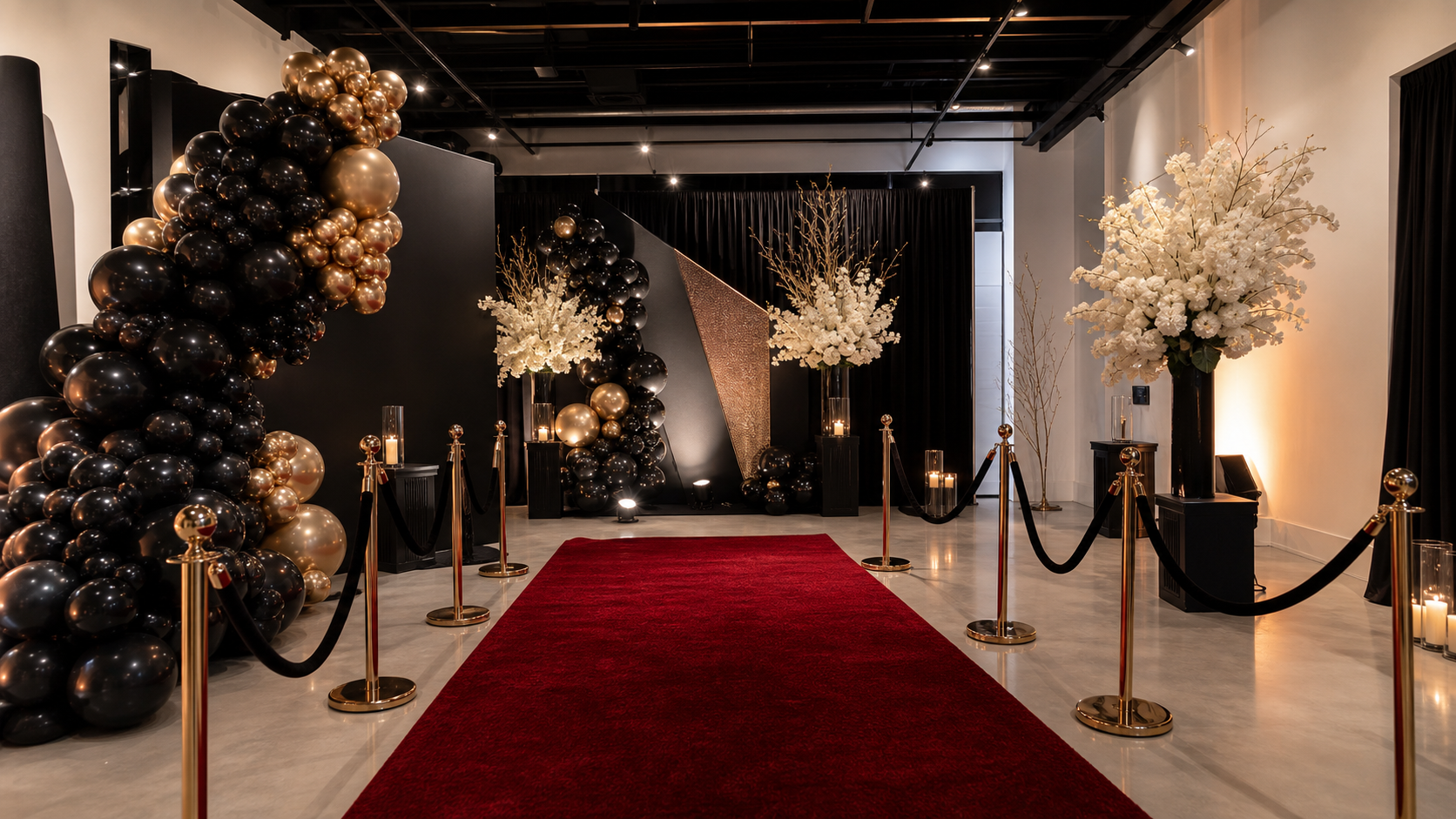 Walk-through balloon garland entrance with a polished red carpet setup